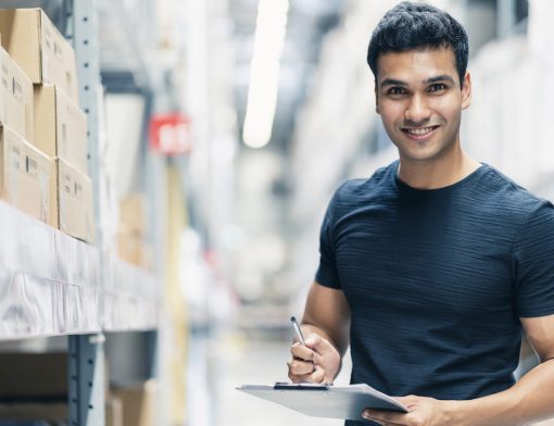 smart-indian-engineer-man-wearing-safety-helmet-doing-stock-tick-check-and-cardboard-stock-product-management-in-factory-warehouse-background