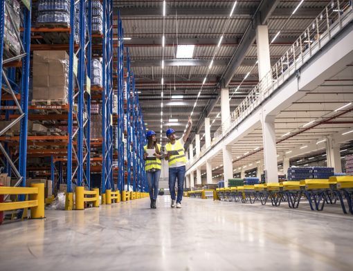 distribution-warehouse-interior-with-workers-wearing-hardhats-and-reflective-jackets-walking-in-storage-area