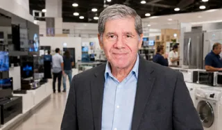 Reinaldo Moura em loja de eletrodomésticos, ao fundo geladeiras e televisores em exposição